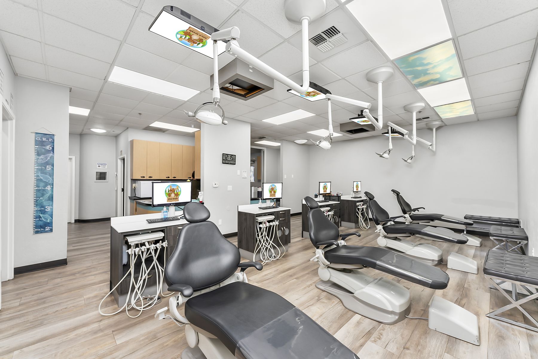 Open treatment bay with sky-and-cloud ceiling panels above each chair