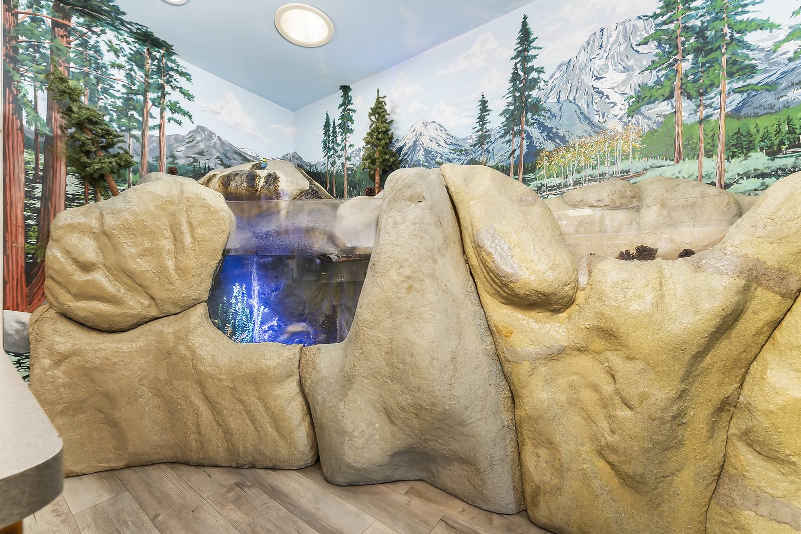 Indoor waterfall built into a rock formation under a painted mountain mural